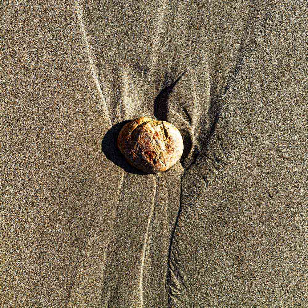 strands | A yellow stone, sand and shadows like vertebrae on a Breton beach