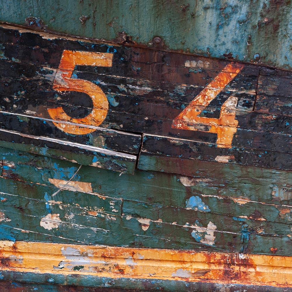 Camaret-sur_mer | a ships registration number in bold numerals on the side of a rotting hulk of a fishing boat with peeling rusty paint