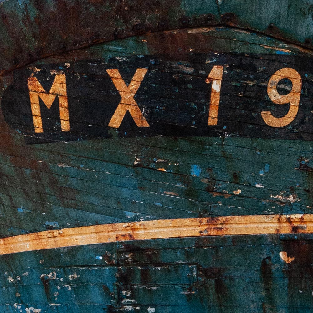 Camaret-sur_mer | The registration number MX19 on side of a rotting hulk of a fishing boat with peeling rusty blue, and yellow paint