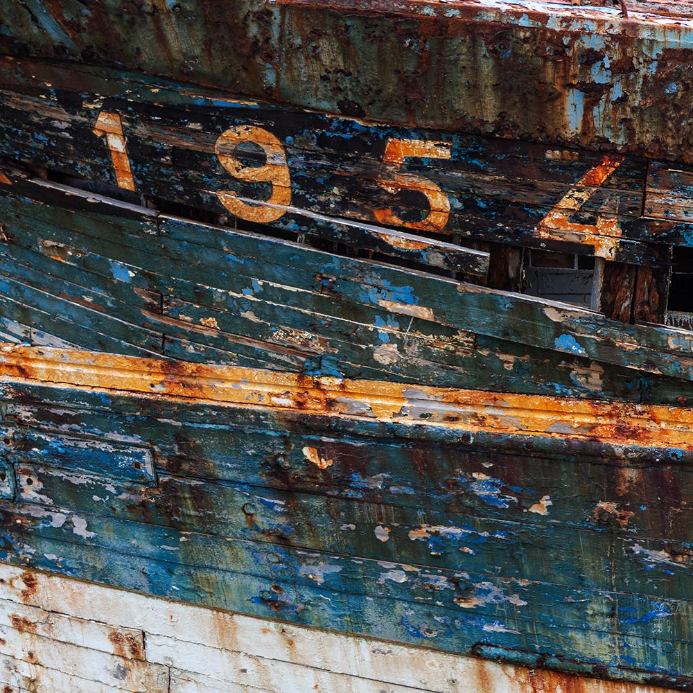 Camaret-sur_mer | The registration number 1954 on side of a rotting hulk of a fishing boat with peeling rusty blue, and yellow paint