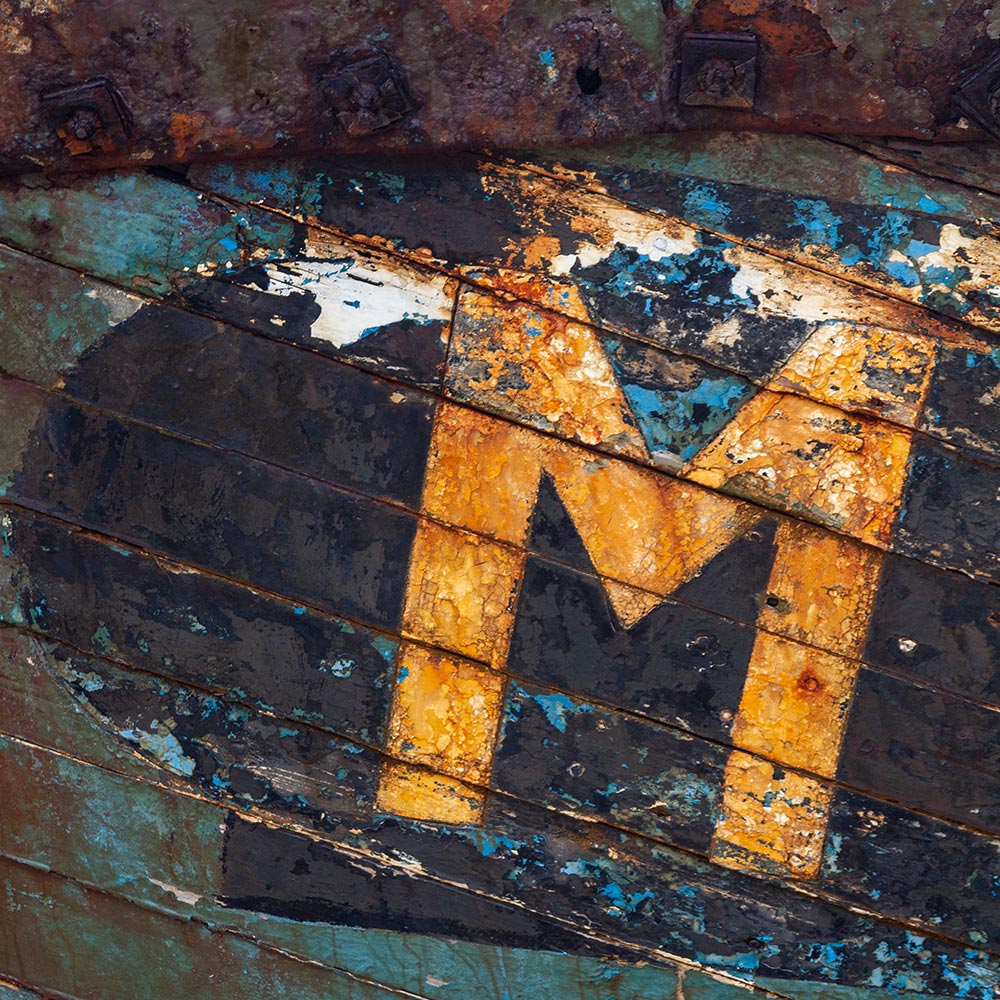 Camaret-sur_mer | The registration number M on side of a rotting hulk of a fishing boat with peeling rusty blue, and yellow paint