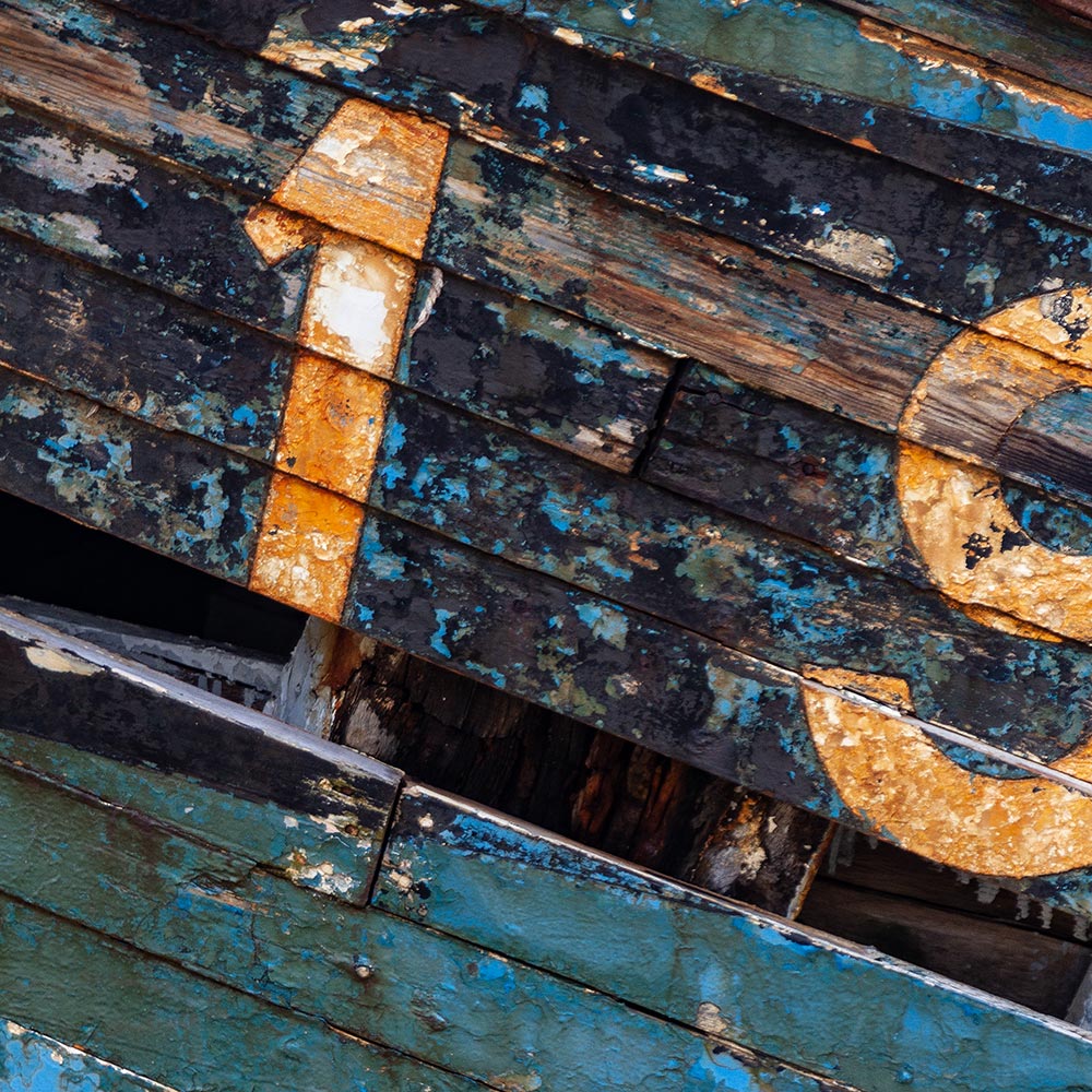 Camaret-sur_mer | The registration number 19 on side of a rotting hulk of a fishing boat with peeling rusty cyan blue, black, white and yellow paint