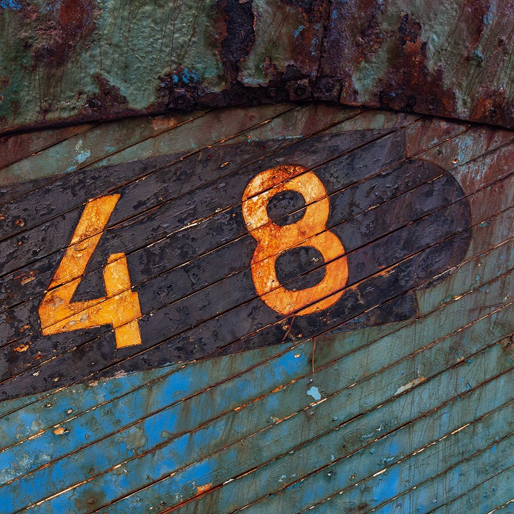 Camaret-sur_mer | The registration number 48 on side of a rotting hulk of a fishing boat with peeling rusty green, brown and yellow paint