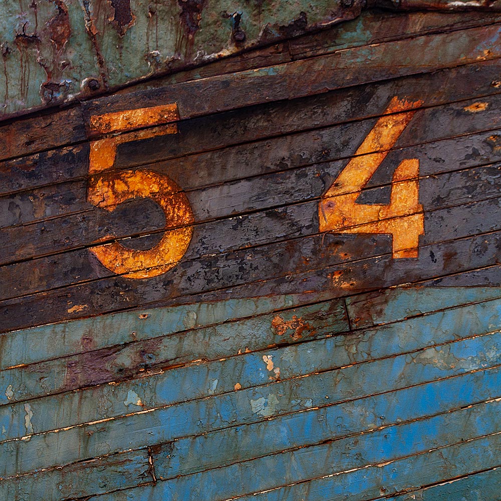 Camaret-sur_mer | The registration number 54 on side of a rotting hulk of a fishing boat with peeling rusty green, brown and yellow paint
