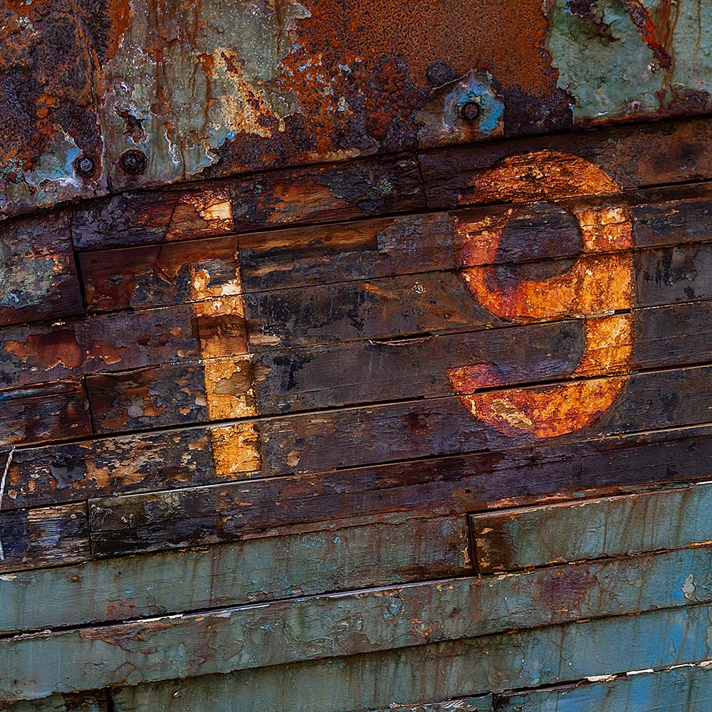 Camaret-sur_mer | The registration number 19 on side of a rotting hulk of a fishing boat with peeling rusty green, brown and yellow paint