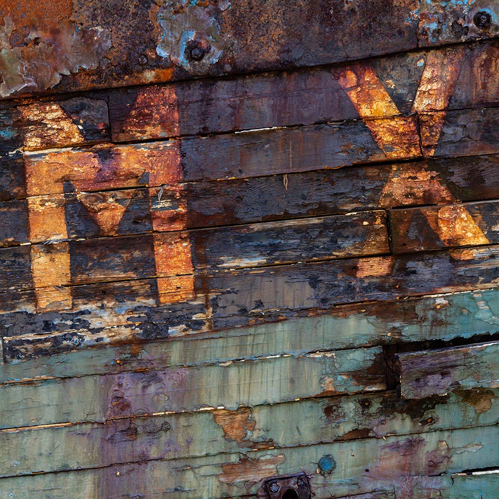 Camaret-sur_mer | The registration number MX on side of a rotting hulk of a fishing boat with peeling rusty green, brown and yellow paint