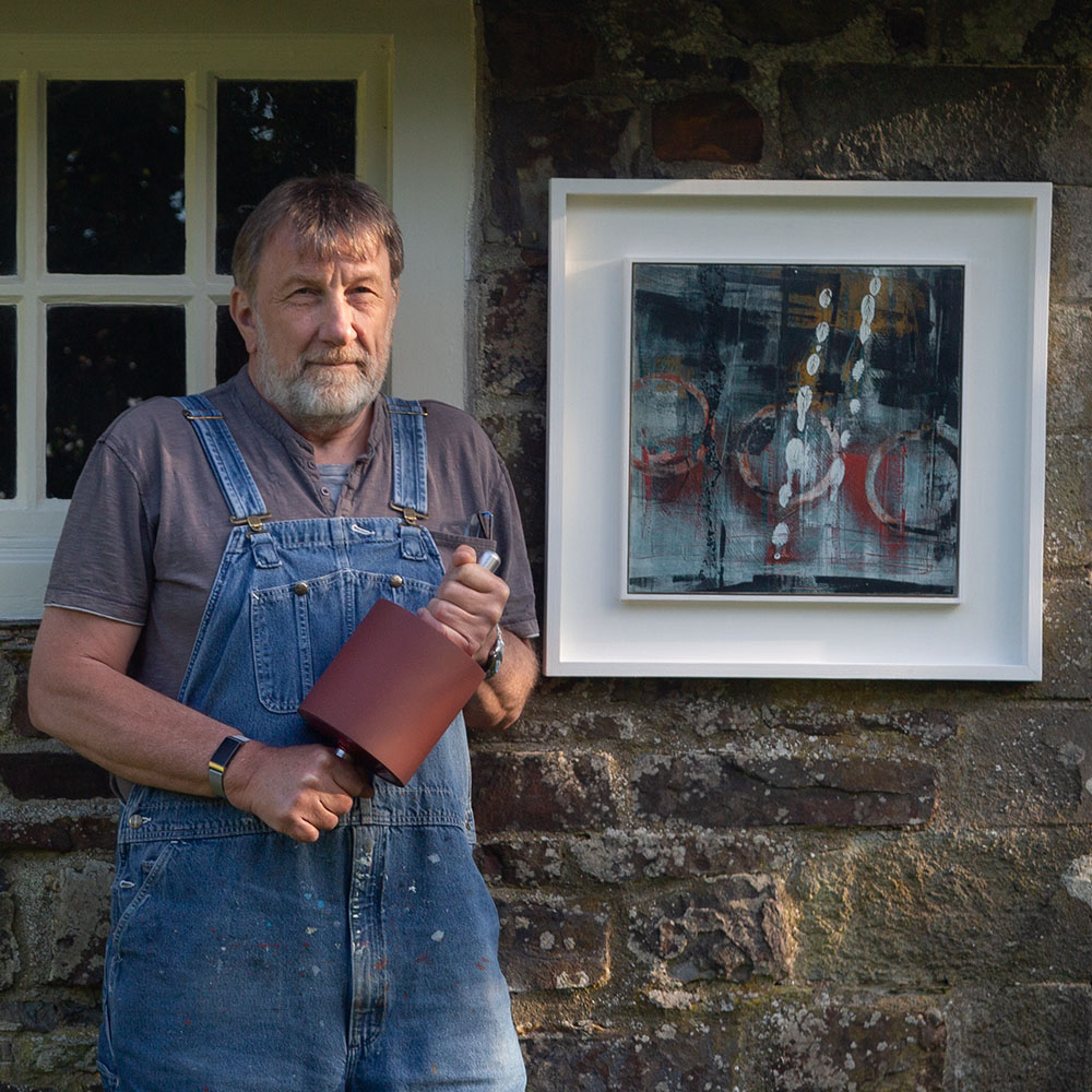 Ian Harrold standing in front of his workshop and an oil painting